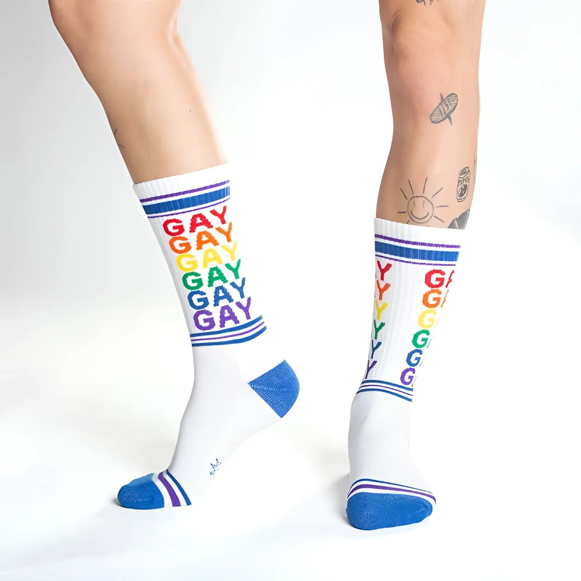 White crew socks with rainbow colored gay text and blue toe heel and cuff accents for pride wear