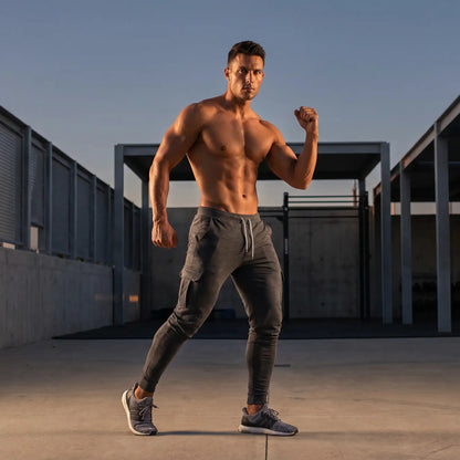 Athletic man in dark gray cargo jogger pants, editorial lifestyle banner for men's athletic pants collection