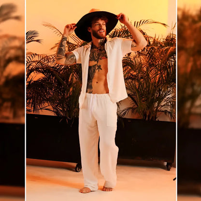 A man wearing gigo chalis beige loose-fitting pants paired with a wide-brimmed black hat and an open white shirt