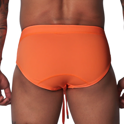 Bright orange swim brief with a wide waistband, contoured back seams, and dangling drawstring against black background.