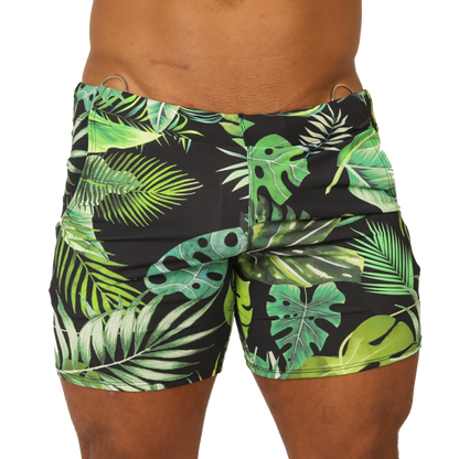 Black swim trunks with vibrant green and lime tropical leaf pattern and metallic silver waistband rings by Gigo Forest