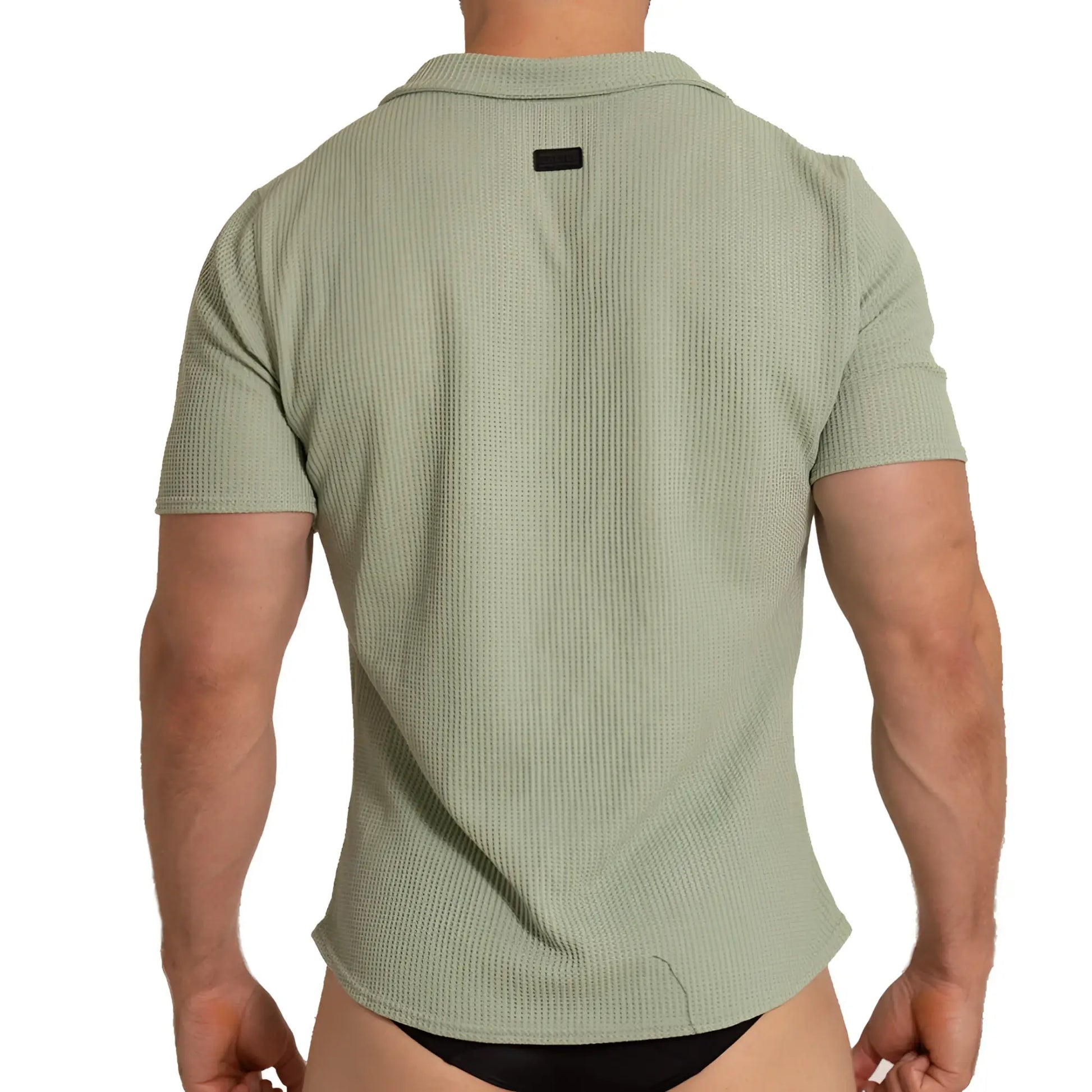 A menâ€™s short-sleeved polo shirt in textured light sage green fabric with ribbed pattern and black collar tag back view