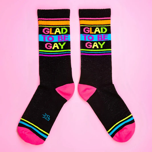 Glad to be gay crew socks with black base rainbow stripes and bold colorful lettering for pride wear