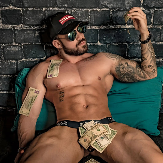 Man wearing black supreme cap and sunglasses lying shirtless against brick wall showcasing good devil gdk043 thong