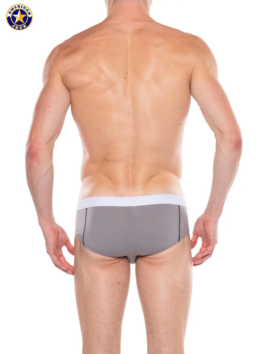 Men's bikini in platinum gray with a white waistband shown from the back on a model by AMERICAN JOCK
