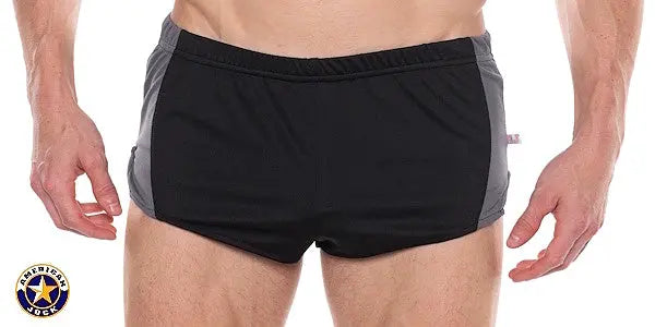 Men's black sprint shorts with gray side panels featuring an elastic waistband shown on a model by AMERICAN JOCK