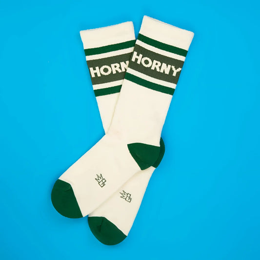 Cream-colored horny crew socks with dark green toe heel and cuff featuring bold white logo on top band