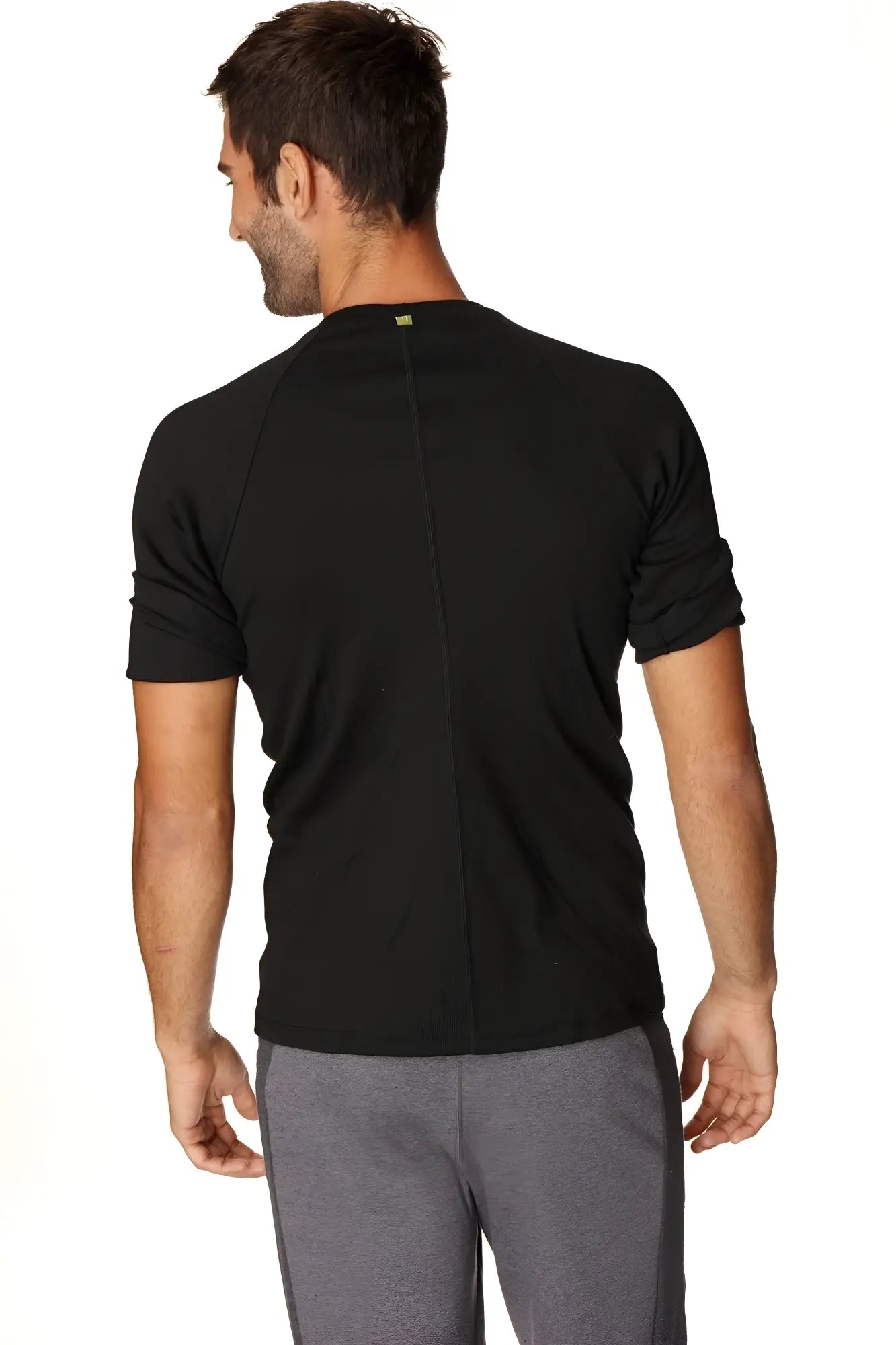 Back view of hybrid crew neck raglan tee black short-sleeved athletic shirt with subtle vertical seam and green logo