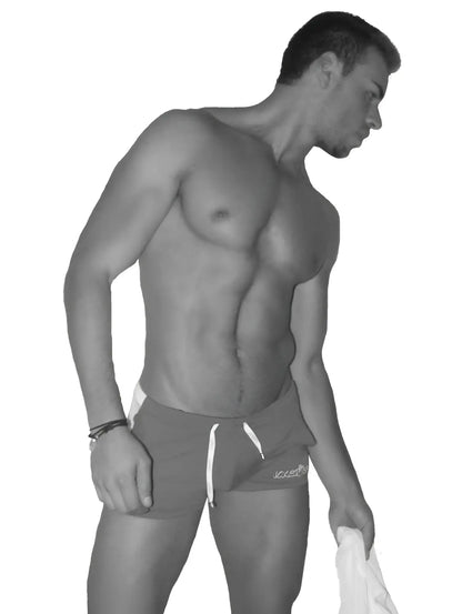 A man wearing icker sea air fitness side stripe shorts in dark color with white drawstrings and logo on the right leg