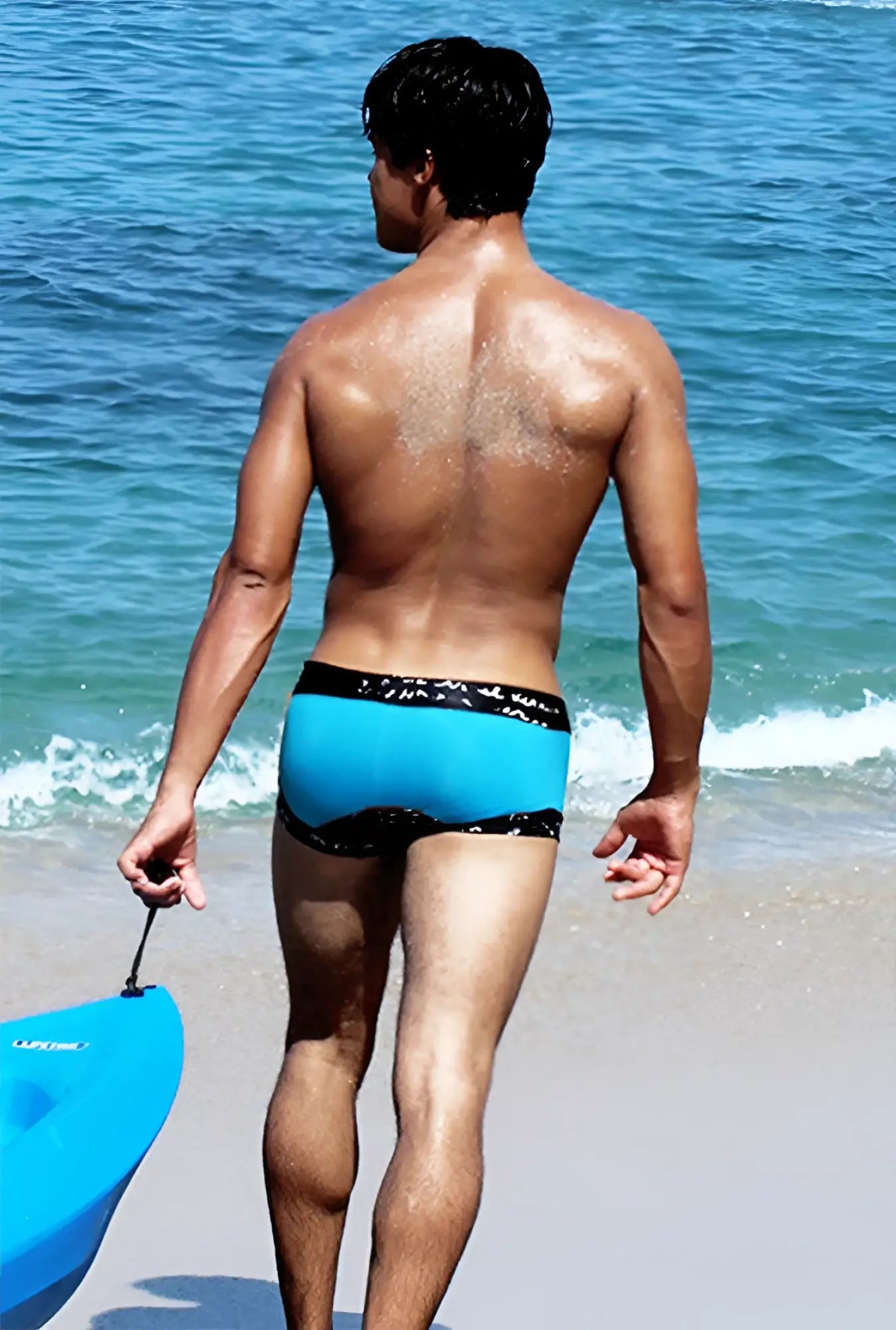 A man stands on the beach wearing icker sea lace up contrast square cut trunk swimwear in blue with black waistband