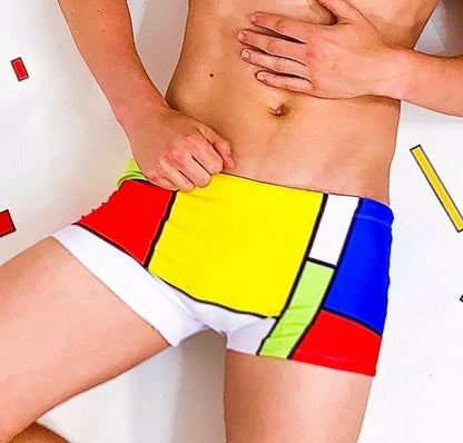 Colorful square cut men's swimsuit by Maris Equi featuring a geometric pattern in yellow red blue and green.