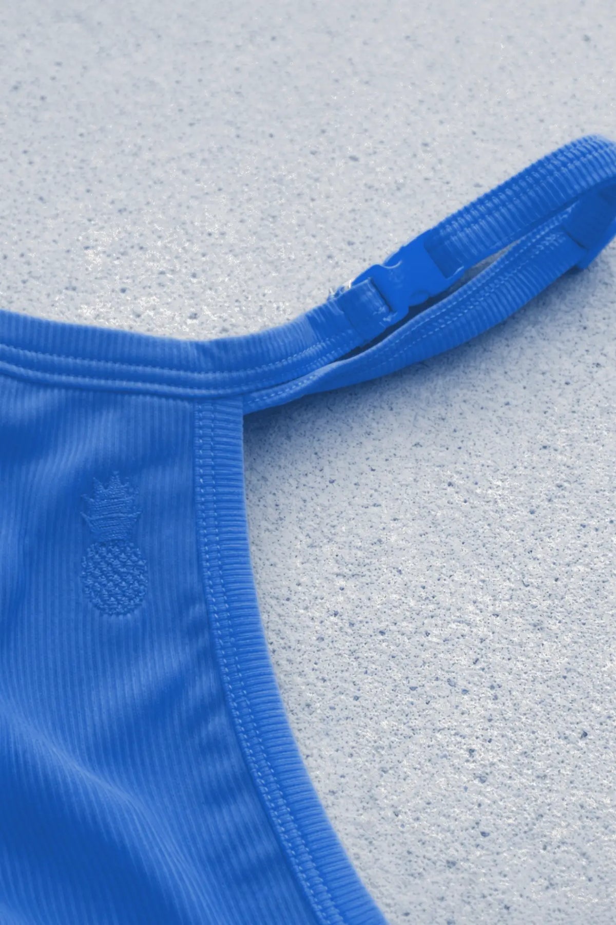 Back view of true blue g string v back jockstrap with ribbed fabric strap, plastic buckle, and embroidered pineapple logo