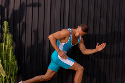 A muscular man wearing a turquoise and white jor 2216 fighter bodysuit made of sleek seamless athletic material