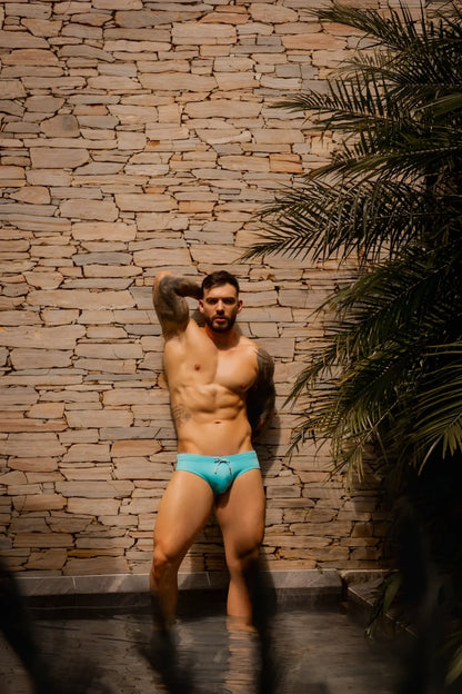 A man wearing jor 2387 travel swim briefs in bright turquoise with a simple drawstring waistband