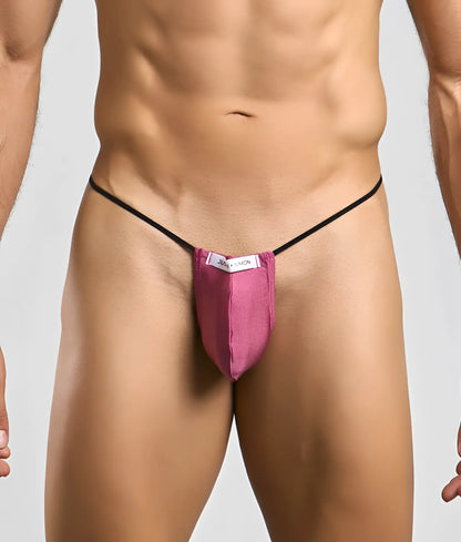 A vibrant pink form-fitting thong with black elastic straps and a white Justin + Simon brand tag shown from the back side