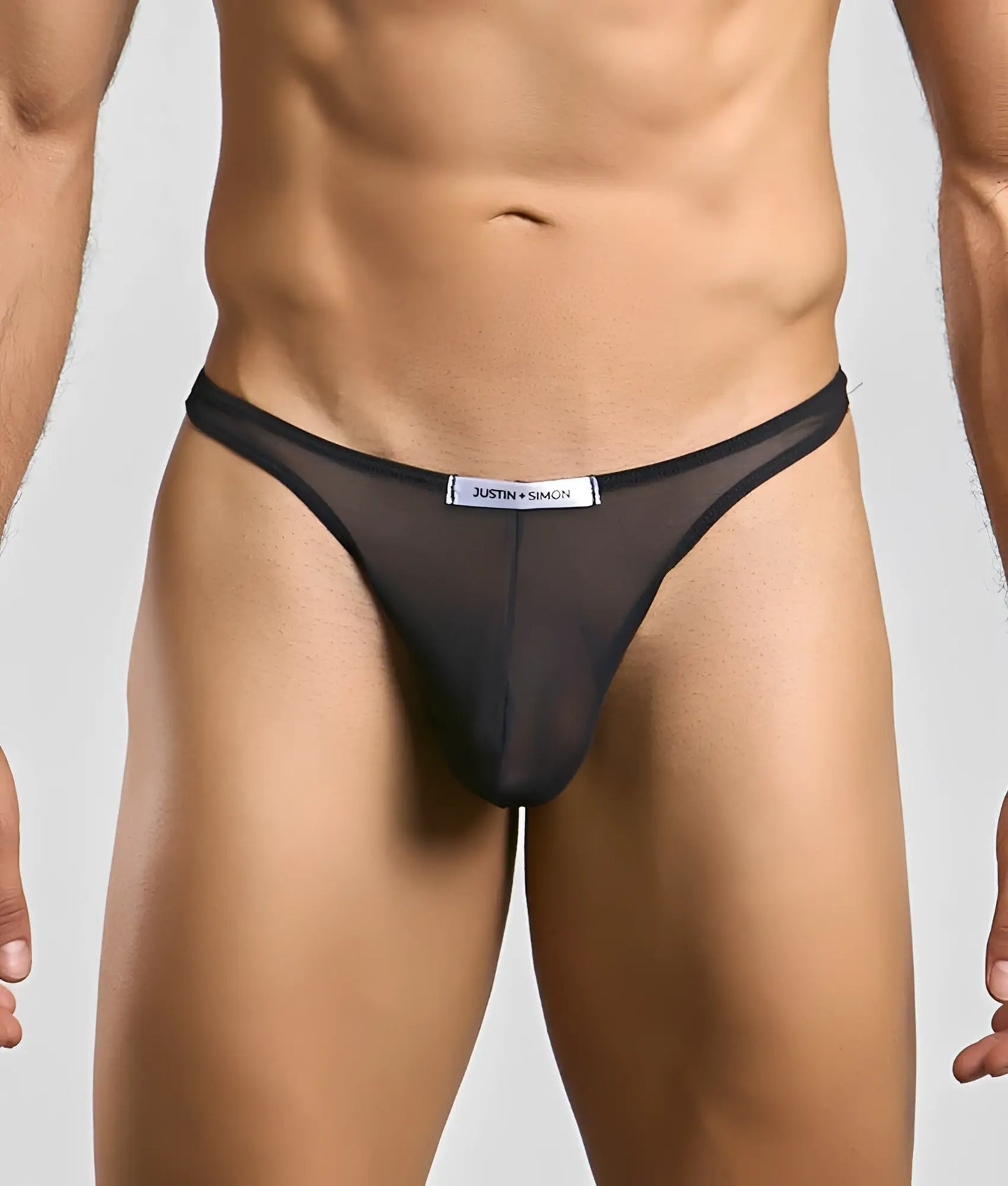 Black sheer mesh thong with a white justin simon label at the waistband from the classic tanga mesh collection