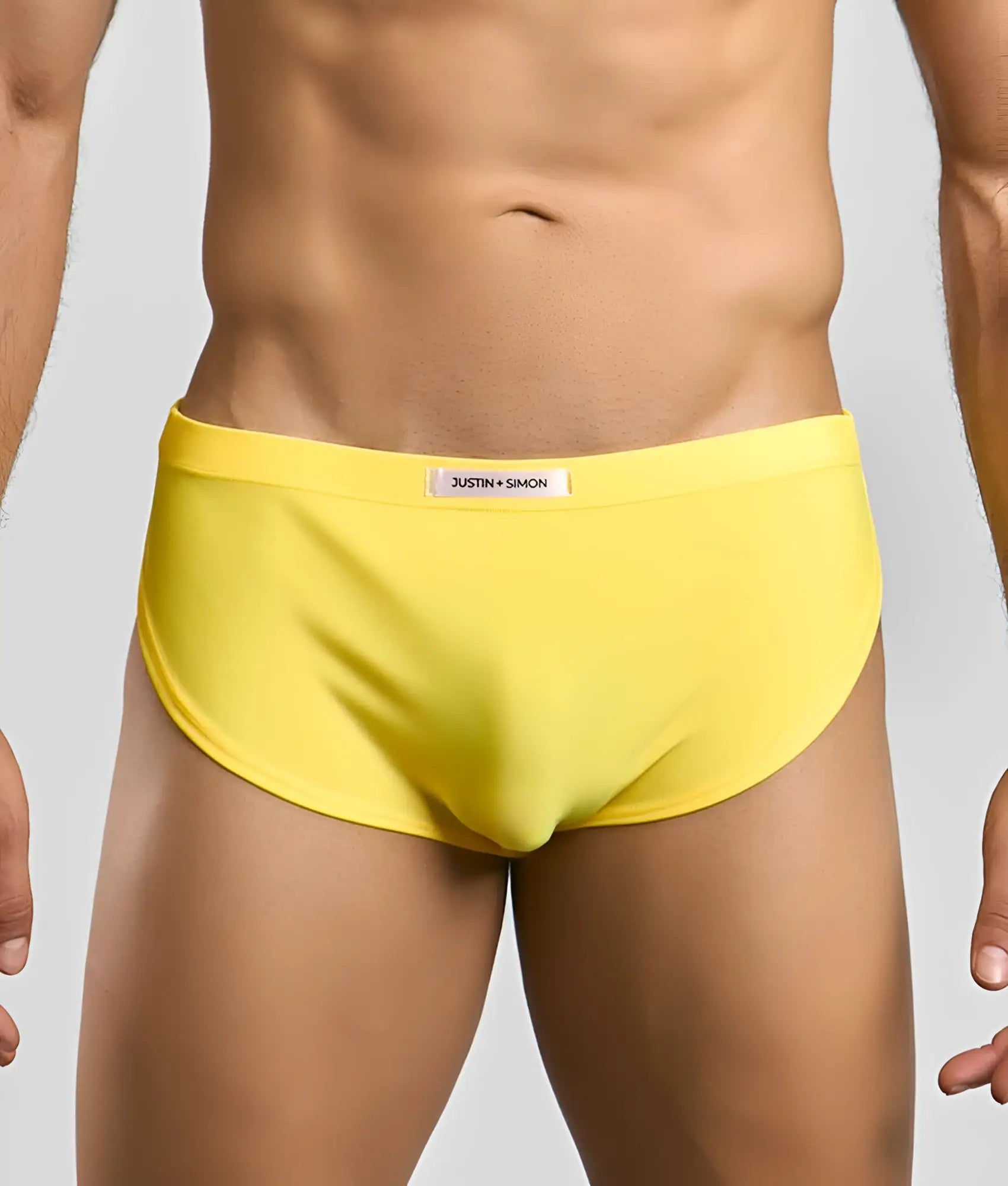 Bright yellow Justin Simon men’s briefs with smooth, form-fitting fabric and subtle waistband branding for running