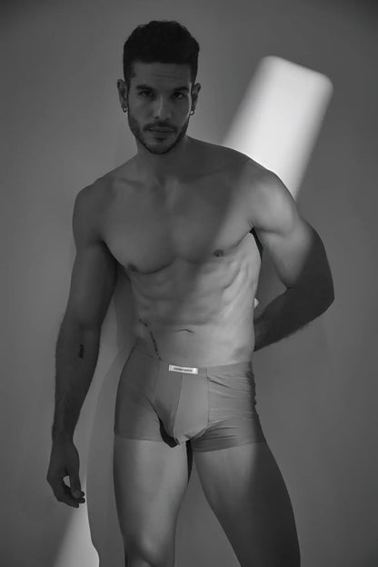 A man wearing light-colored form-fitting calvin klein classic boxer briefs with a metal green waistband label