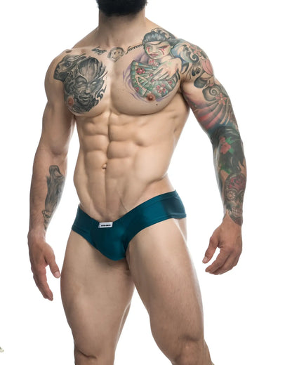 Teal JUSTIN+SIMON XSJ22 cheek briefs with a small white brand tag on the waistband in opal green color