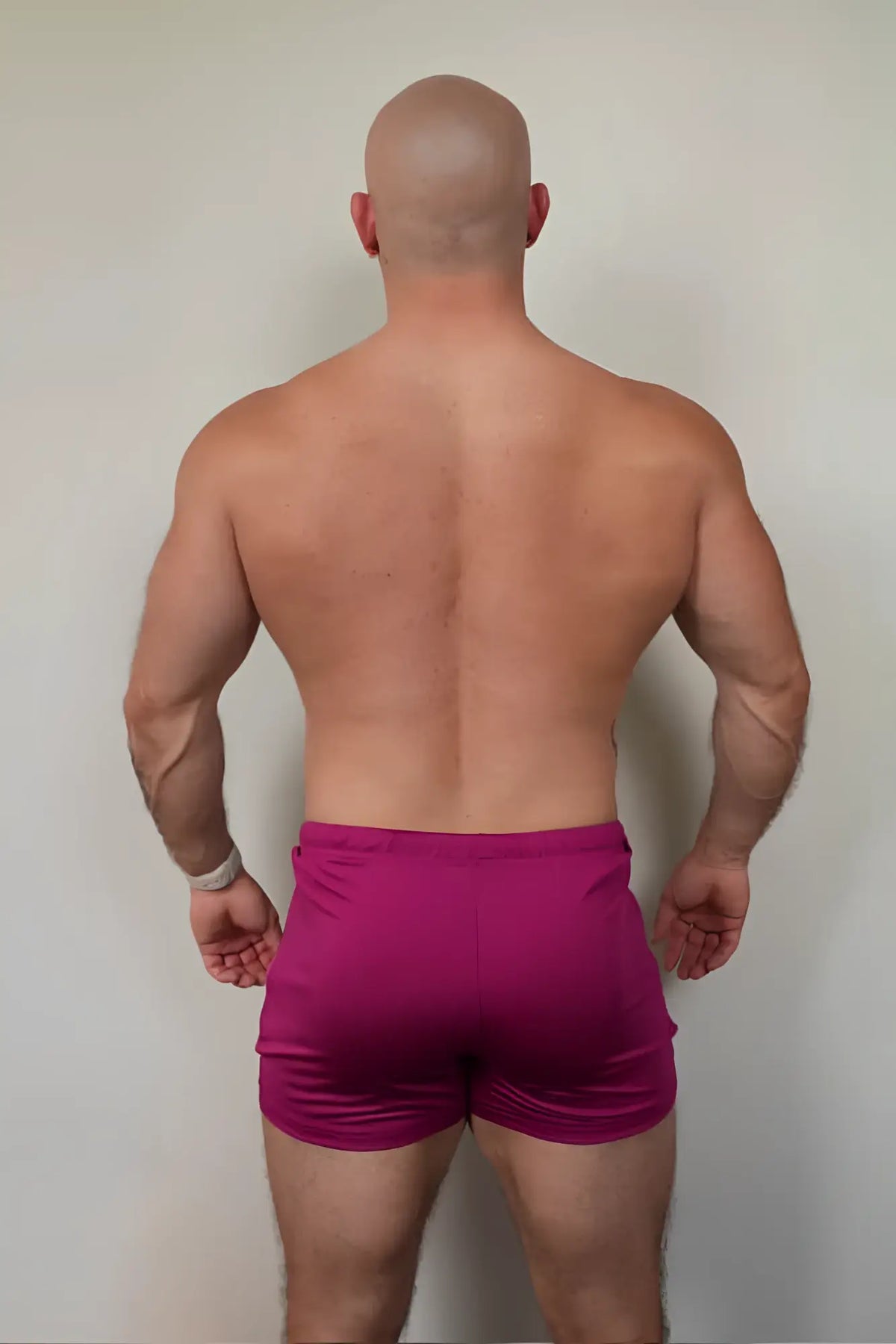 A pair of vibrant magenta karma 2 inch short shorts with elastic waistband and zipper pockets for athletic use