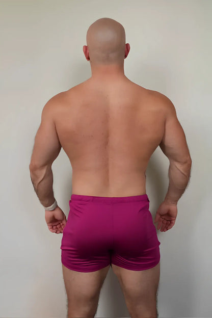 A pair of vibrant magenta karma 2 inch short shorts with elastic waistband and zipper pockets for athletic use
