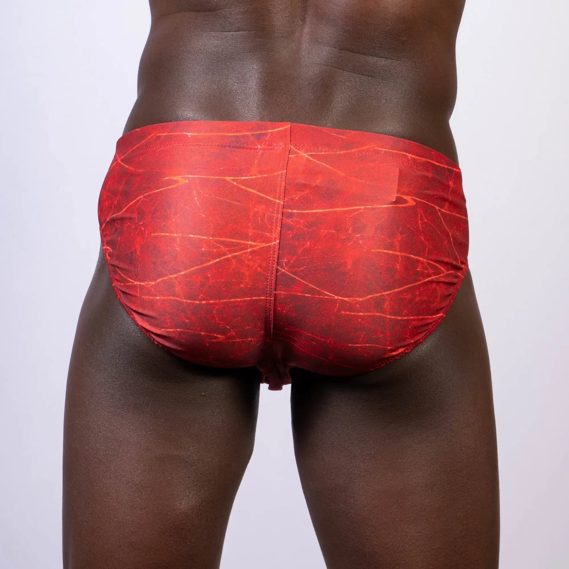 Red swim trunks with a marbled pattern featured in the lightning swim brief for stylish beachwear