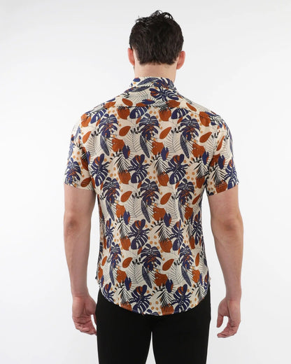 A man wearing a lightweight linen tencel short-sleeved shirt with a tropical leaf and fruit pattern on beige