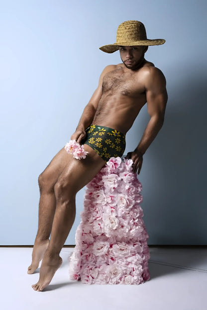 A man wearing male power petal power pouch short daisy print in green floral pattern with pink roses on legs