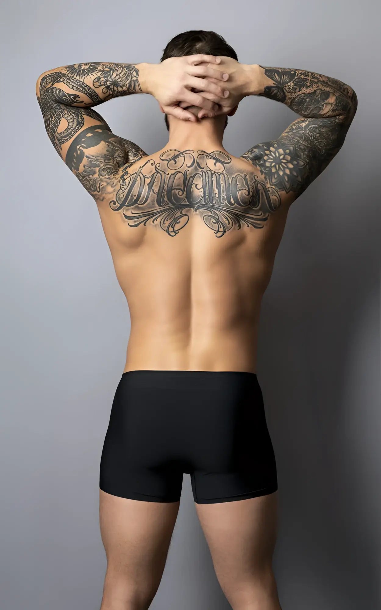 A man wearing male power 154-300 hot mesh pouch short black red showing the back with black ink tattoos