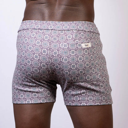 Back side of gray and white mandala linen texture shorts with a circular pattern and brand tag on the waistband