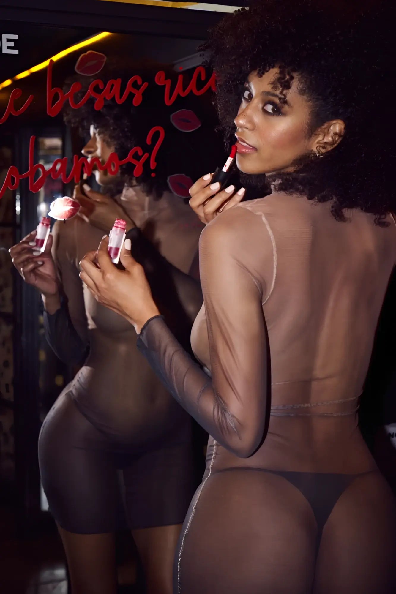 A woman in a sheer black Mapale 40000 bodysuit holds red lipstick wearing the midnight shadow dress color