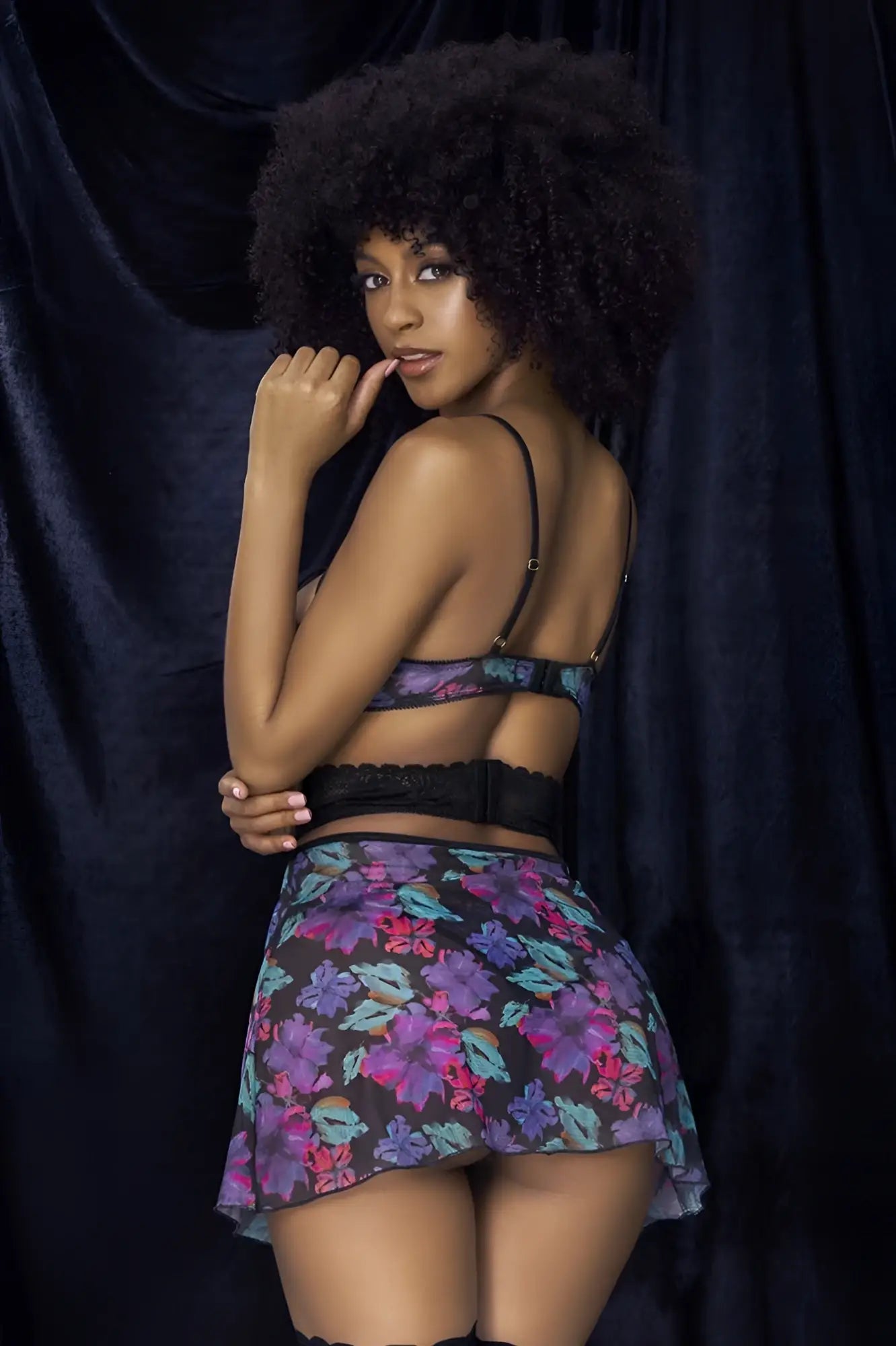 A woman wears a Mapale 7496 babydoll three piece set with a black lace bra and floral mini skirt in vibrant colors