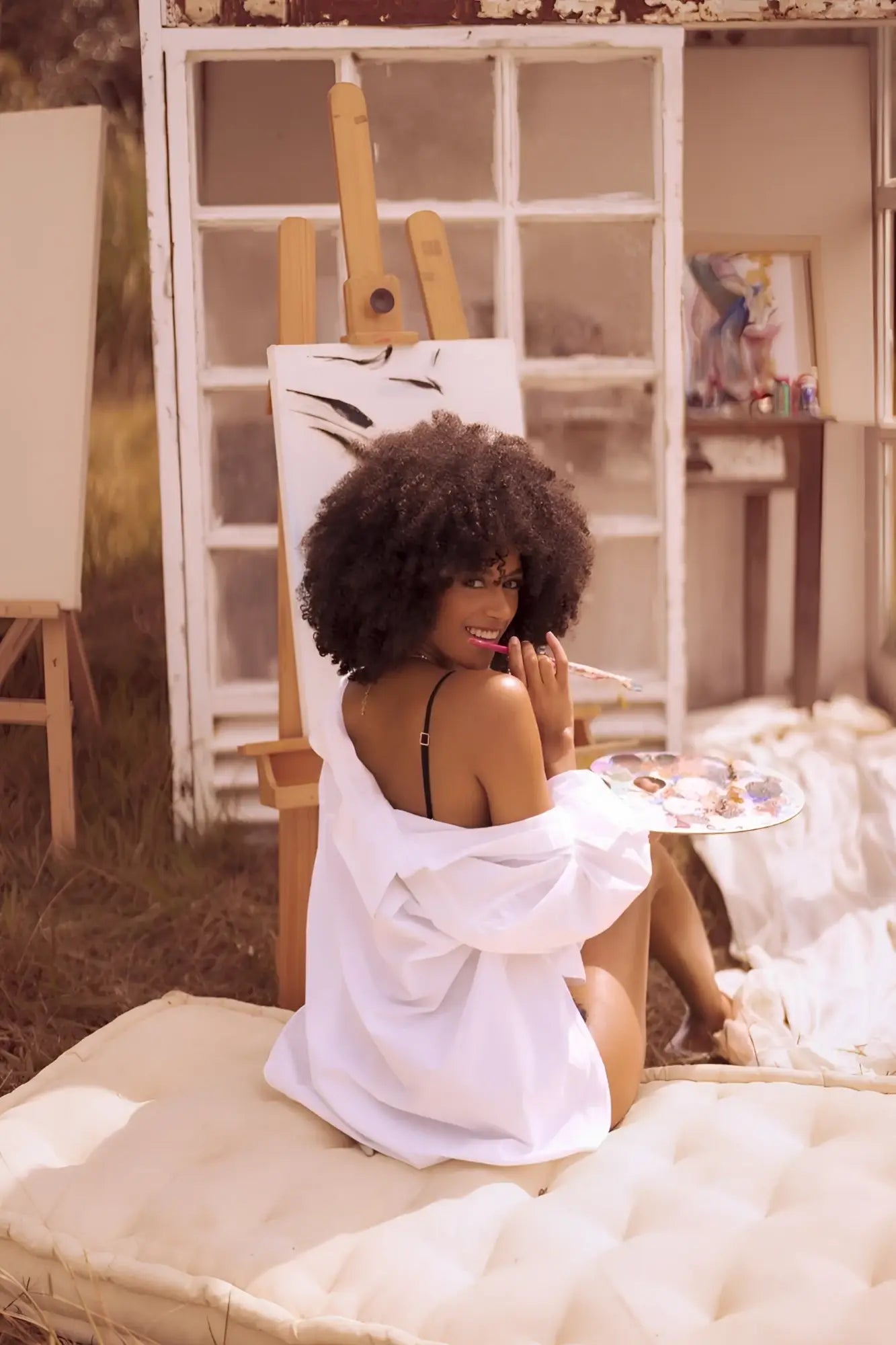 A woman sits on a tufted white cushion wearing Mapale 8864 night butterfly two piece black lingerie set with white shirt