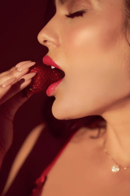 A woman with glossy red lips bites a ripe strawberry wearing a Mapale 8899 black-red two piece set