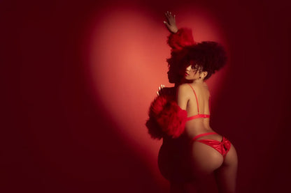 A woman wearing the mapale 8901 red two piece satin lingerie set with matching feathered shoulder accents