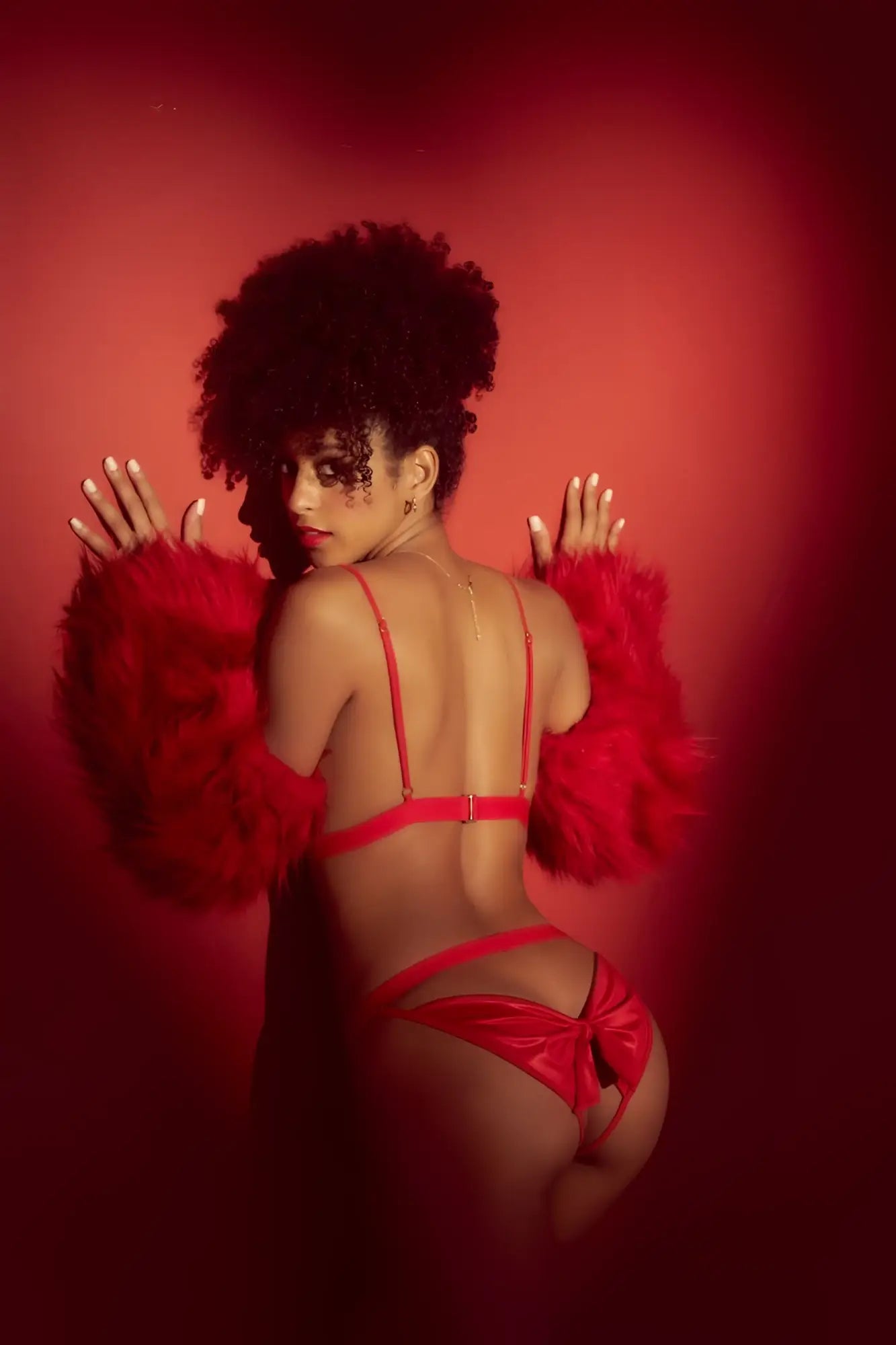 A woman wears a mapale 8901 two piece set in vibrant red satin lingerie with thin straps and feathered arm accessory