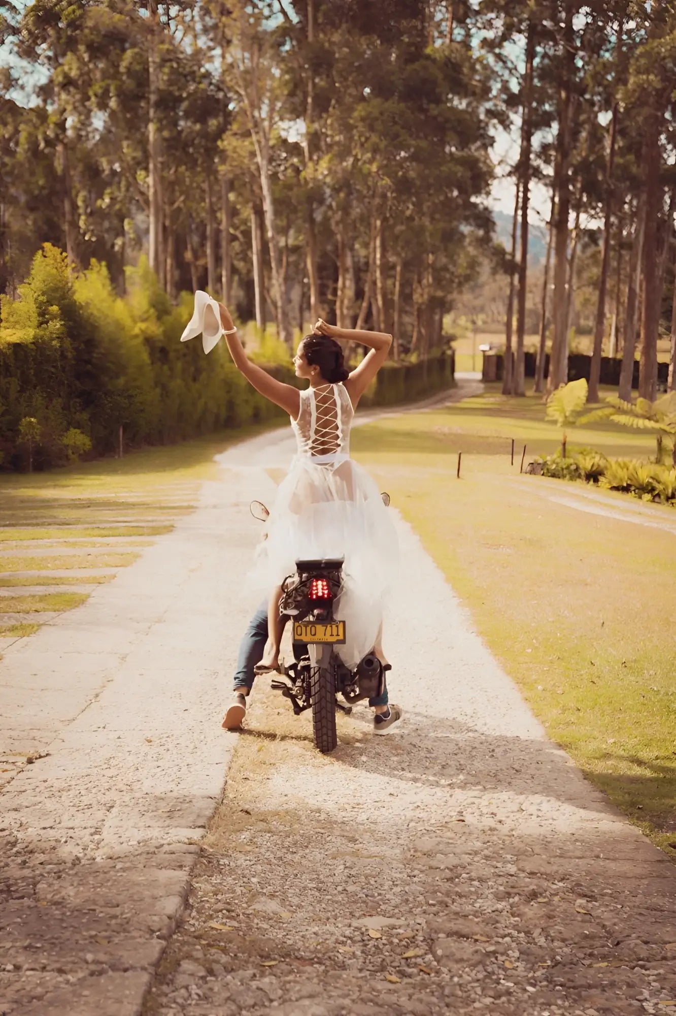 A bride wearing the back of mapale 8932 white lace teddy rides a motorcycle holding up her veil