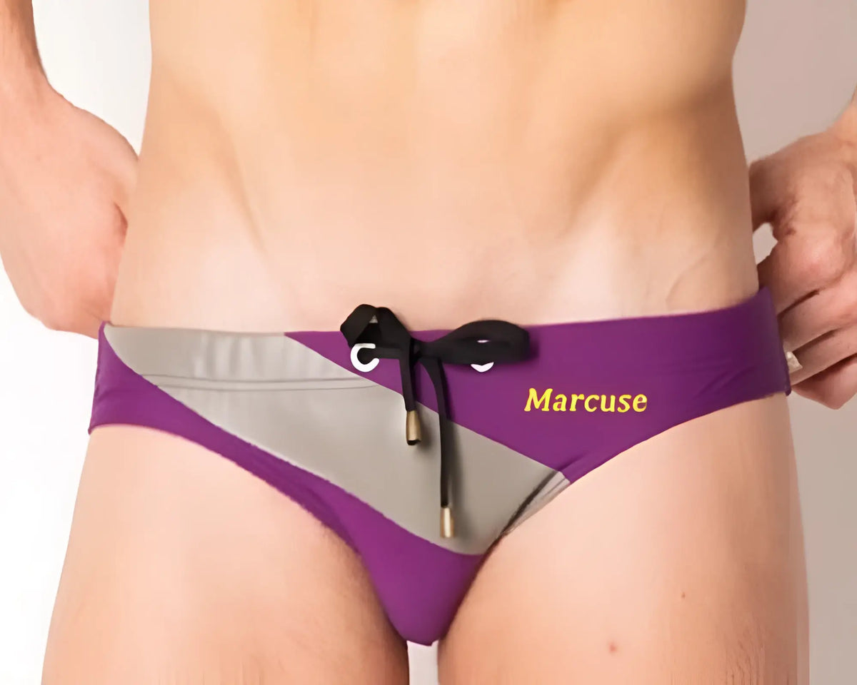Purple and gray striped marcuse ma_xtreme swimwear trunks with black drawstring tie and gold marcuse branding