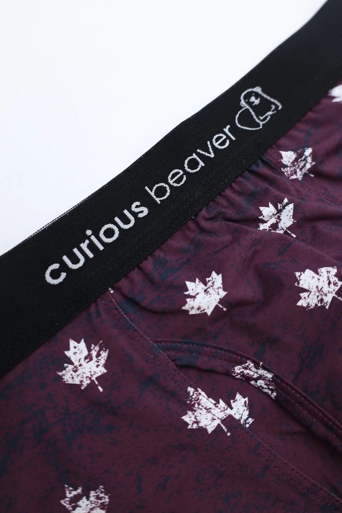 Menâ€™s maroon boxer briefs with white maple leaf pattern and black elastic waistband featuring curious beaver brand name