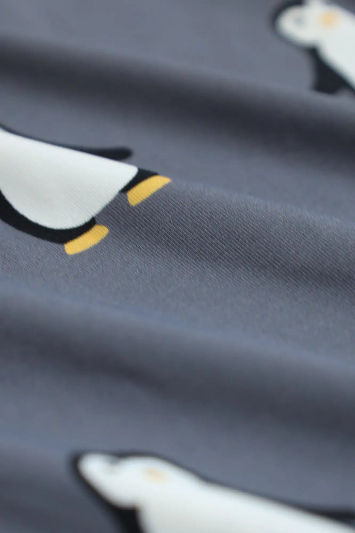 Menâ€™s boxer briefs in gray fabric with a repeating pattern of cartoon penguins with white bodies and yellow feet