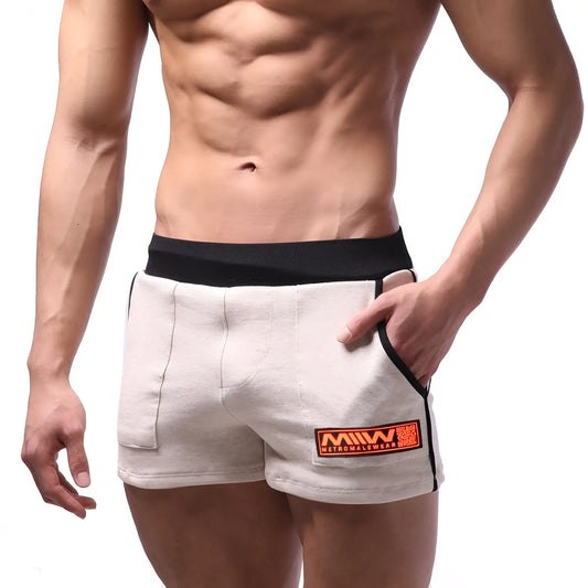 Beige cotton athletic shorts with black elastic waistband and orange logo patch by metromalewear for sports use