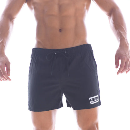 Black athletic swim shorts with drawstring waistband and white logo patch on lower right leg by metromalewear
