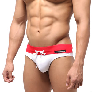 White swim trunks with bold red waistband and white drawstring featuring metromalewear label for swimming use