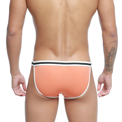 Coral-colored metro malewear link bikini briefs with white and black striped waistband in front view