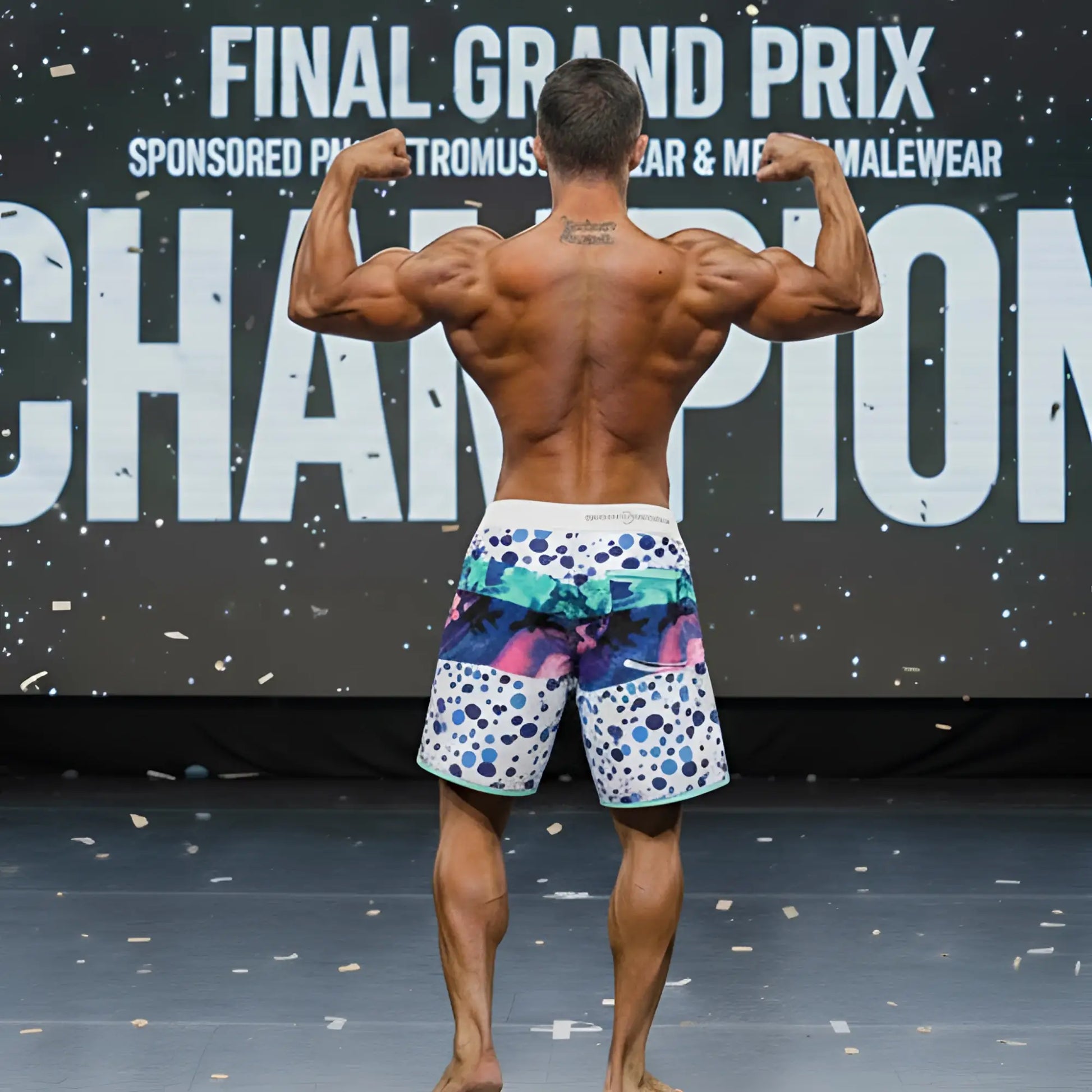 A man wearing MetroMaleWear MetroMuscleWear bubble physique board shorts with vibrant blue pink and teal patterns