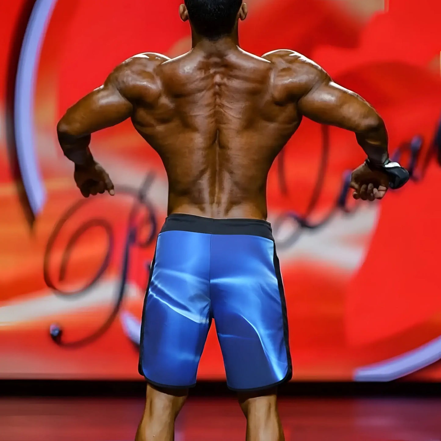 Blue metromalewear IFBB Pro mens physique board shorts with glossy reflective finish and black trim for athletic use