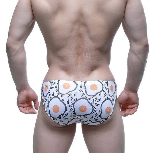 White swim trunks by metromalewear with playful fried egg pattern accented by black outlines and lines