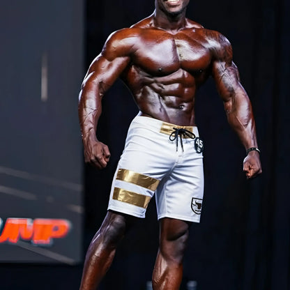 White MetroMaleWear Physique board shorts with gold stripes black logo on left leg and drawstring waistband