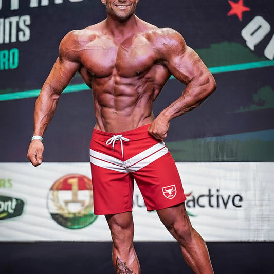 Red athletic board shorts with white stripes and a small bull logo on the left leg by metromalewear