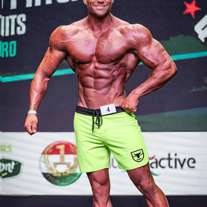 MetroMaleWear physique board short lime-black with bright neon green fabric, black waistband, drawstring, and shield logo